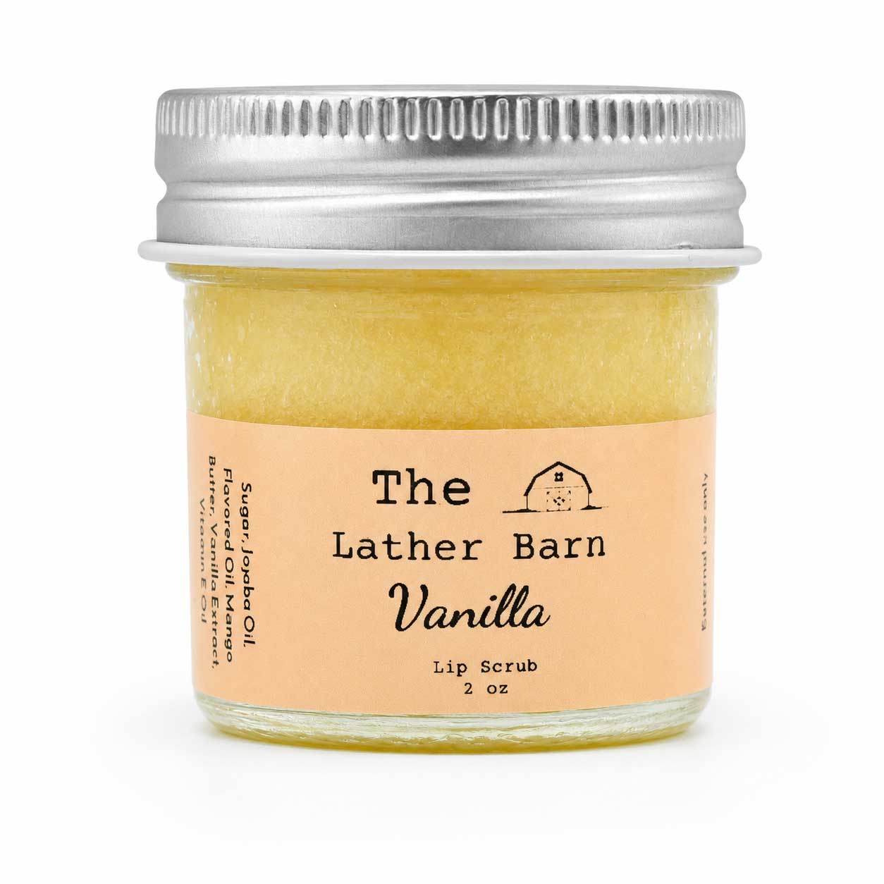 A small glass jar of lip scrub with a silver metal lid and a peach label reading 'The Lather Barn Vanilla Lip Scrub 2 oz' on a white background.