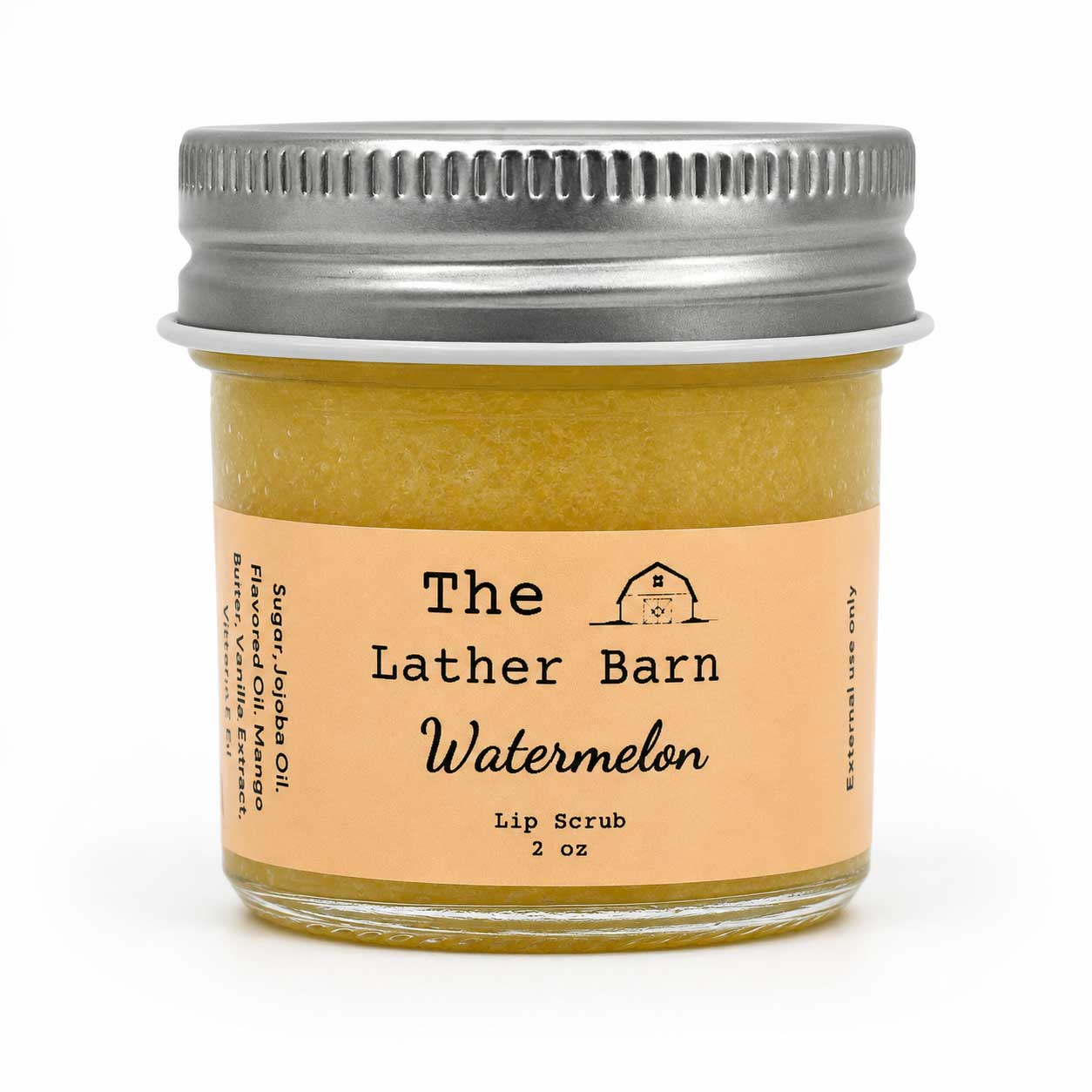 A jar of The Lather Barn Watermelon lip scrub with a silver metal lid and a peach-colored label, set against a plain white background.