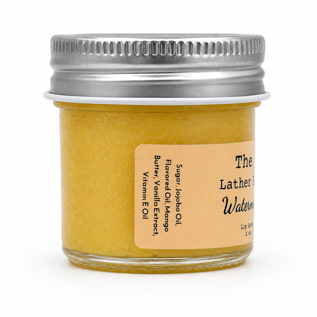 A small glass jar filled with a yellow lip balm or wax product, sealed with a silver metal screw lid and labeled 'The Lathered Watermelon' on a white background.