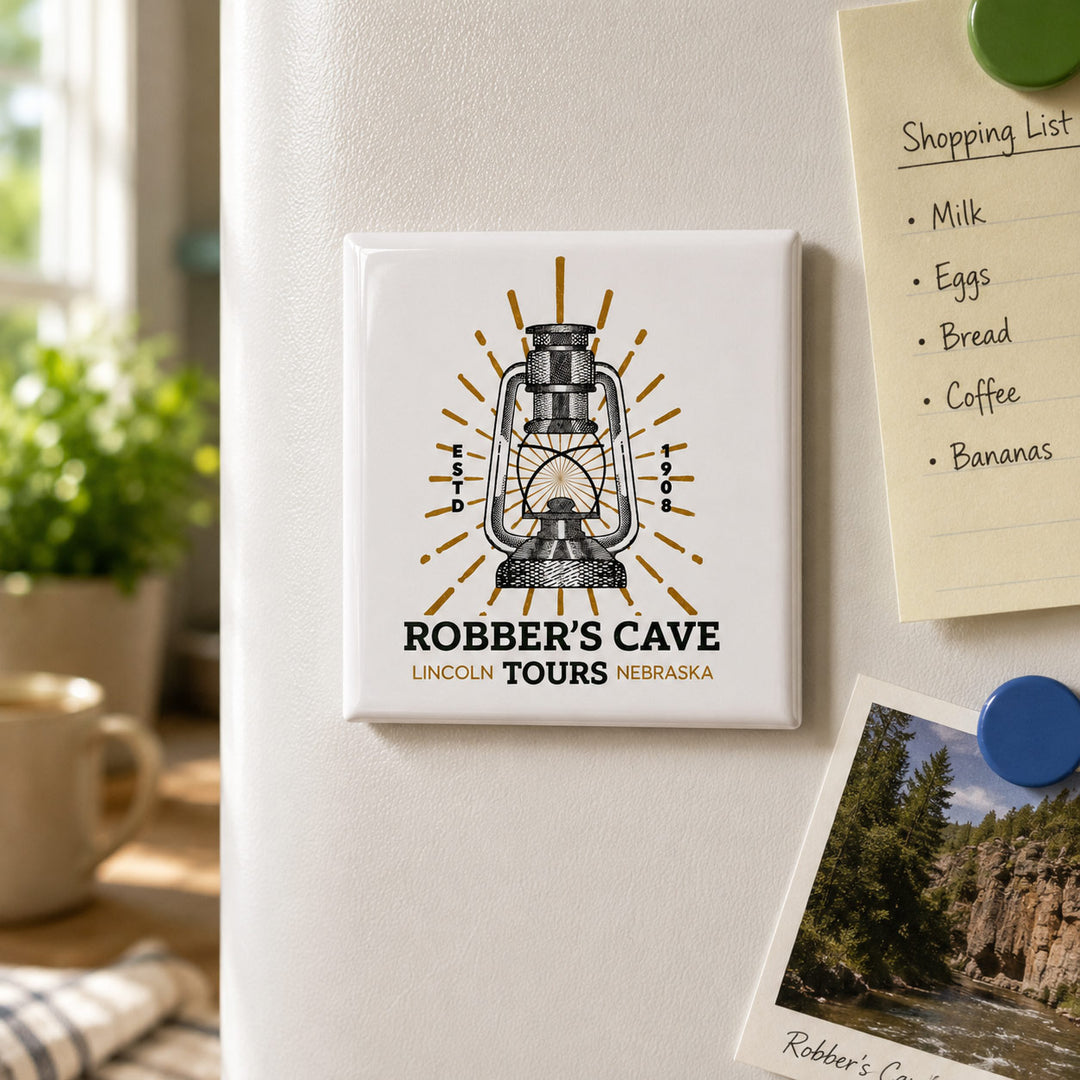 A square white refrigerator magnet featuring a vintage lantern illustration and the text 'ROBBER'S CAVE LINCOLN TOURS NEBRASKA' is shown attached to a white refrigerator. The fridge is in a kitchen setting with a shopping list note and a photo pinned nearby.