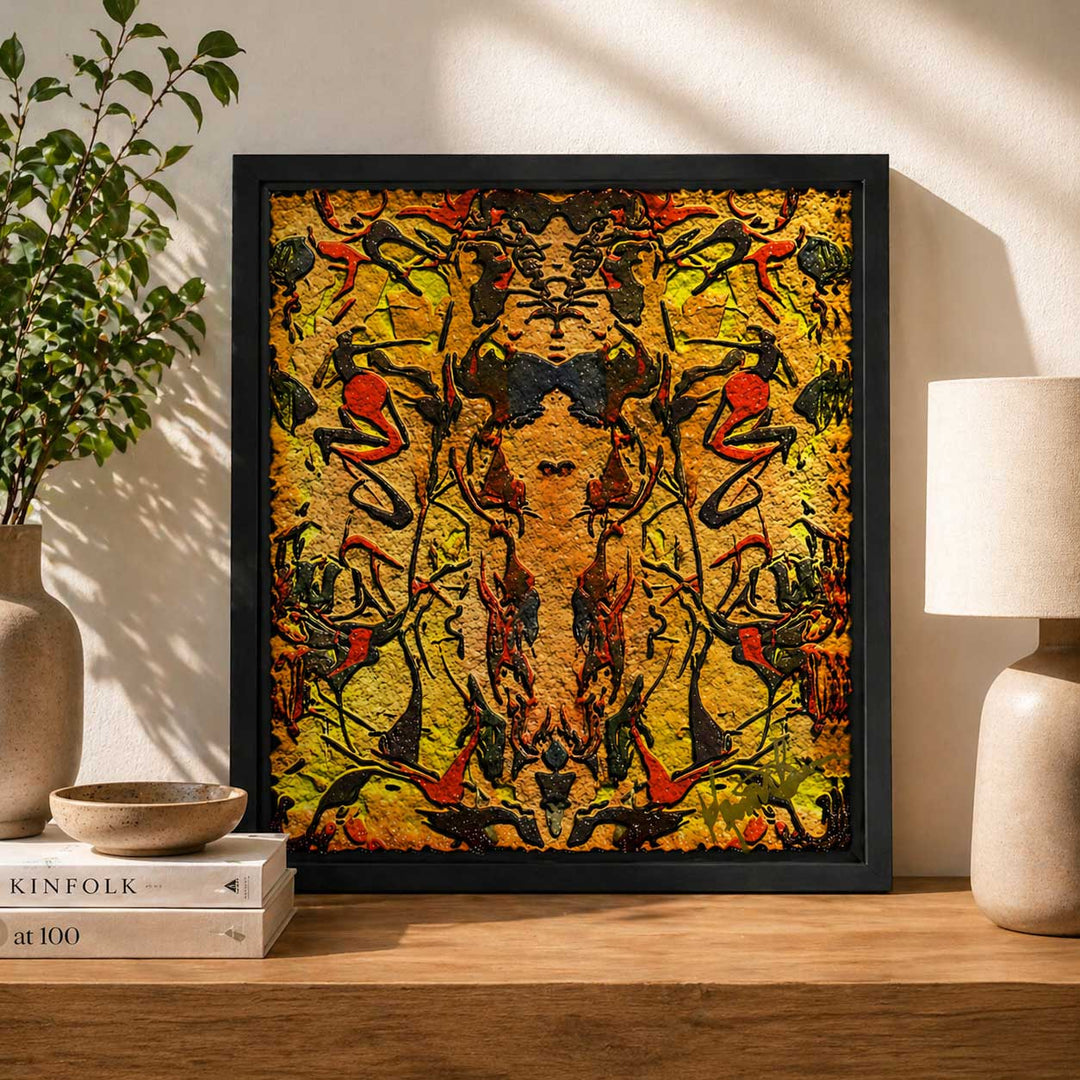 Framed abstract artwork on a wooden shelf with a plant and lamp in the background