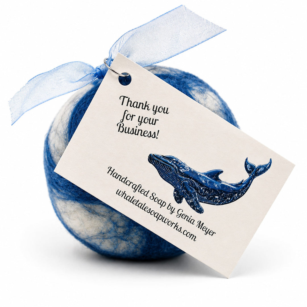 Blue and white bath bomb with a whale design and 'Handcrafted Soap by Genia Mayer' tag on a white background