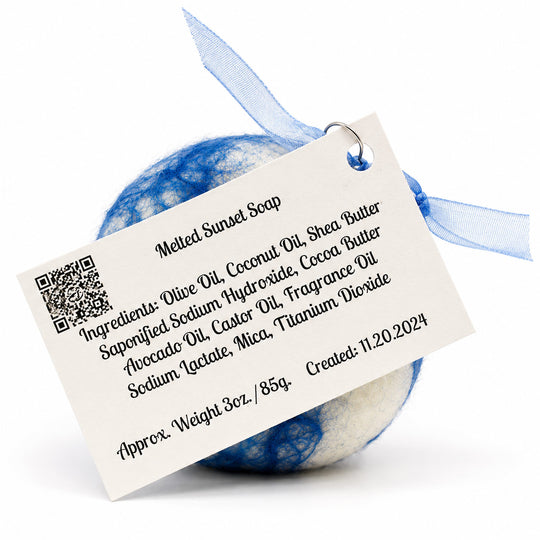 Blue and white bath bomb with a label detailing ingredients and creation information on a white background