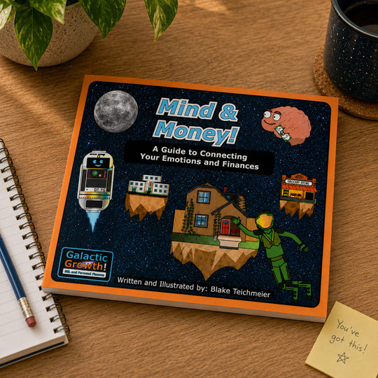 A hardcover book titled 'Mind & Money! A Guide to Connecting Your Emotions and Finances' by Blake Teichmeier, placed on a wooden desk next to a notebook, pencil, plant, and a sticky note that says 'You've got this!'.
