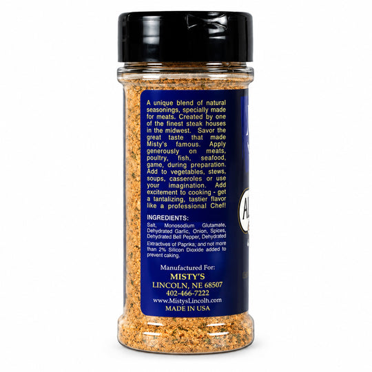 A clear plastic spice bottle with a black lid and a dark blue label, showing a blend of brown and orange seasoning inside. The label reads 'A Taste of差异' at the top and details ingredients and manufacturer information for Misty's Lincoln, Nebraska.