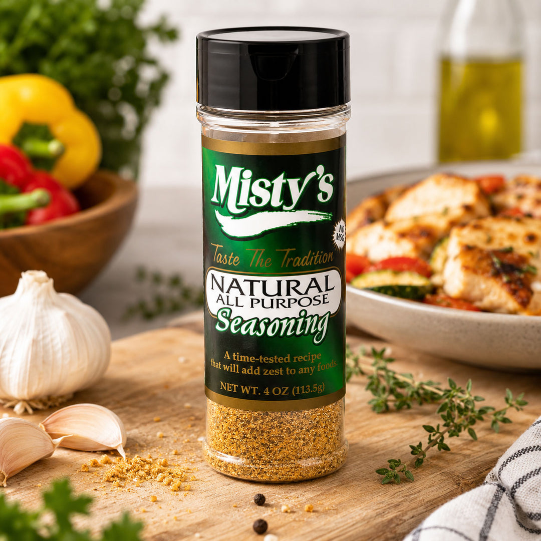 Bottle of Misty's Natural All Purpose Seasoning on a wooden surface with ingredients in the background