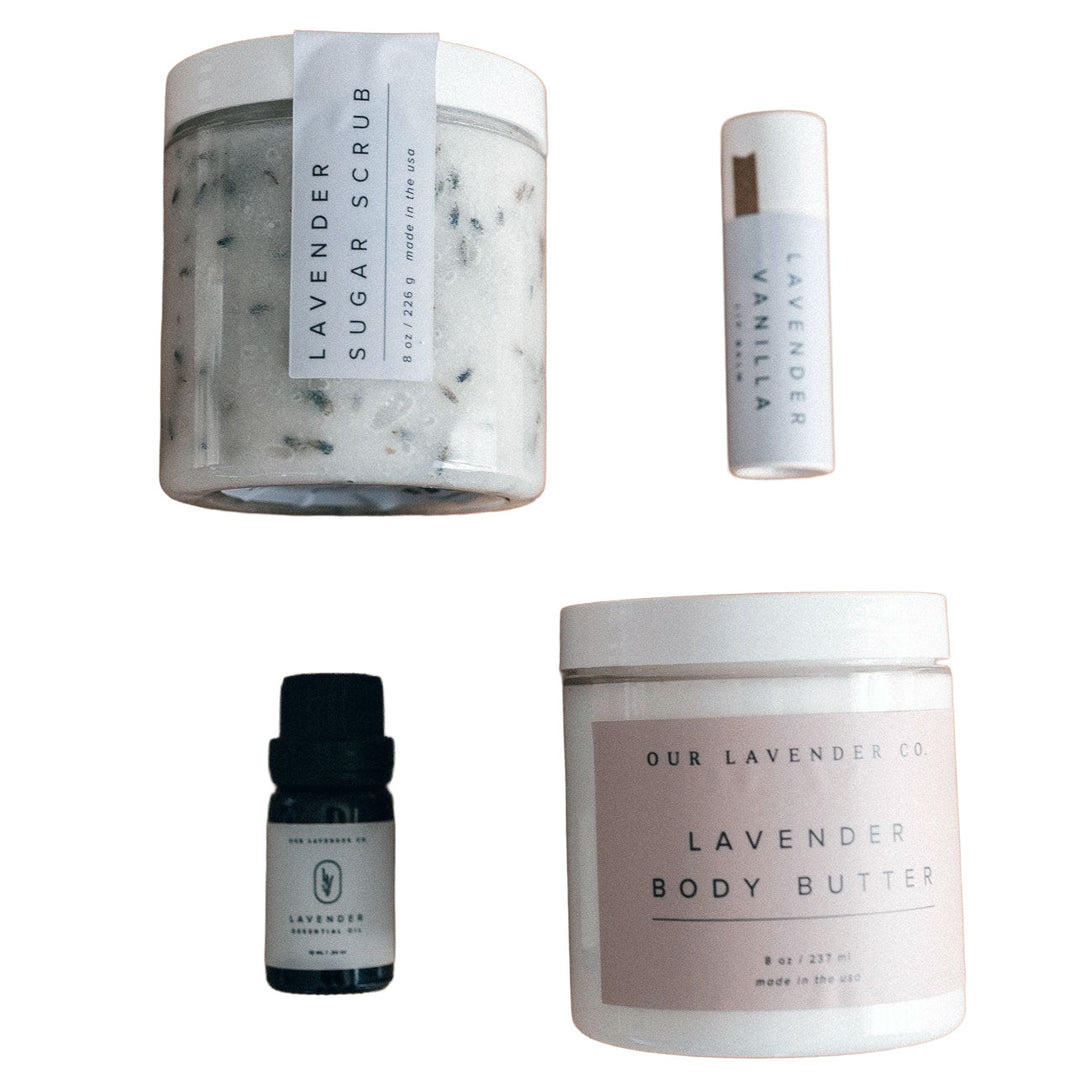 Collection of lavender-themed skincare products including a sugar scrub, body butter, and essential oil on a white background.