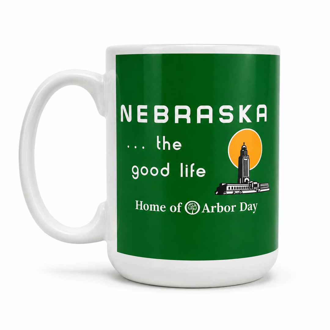 A white ceramic mug featuring a green wraparound graphic with the text 'NEBRASKA .