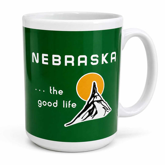 A white ceramic coffee mug with a dark green wraparound graphic that reads 'NEBRASKA .