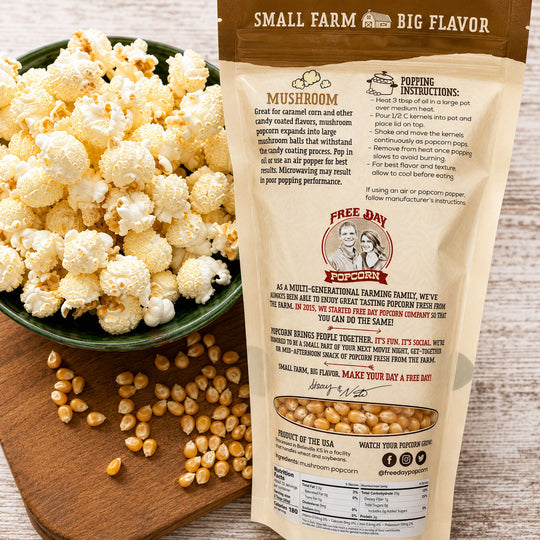 Mushroom popcorn package with a bowl of popcorn and kernels on a wooden board.
