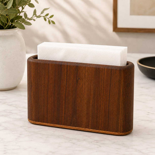 Wooden napkin holder with white paper towels on a countertop.