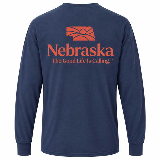 A navy blue long-sleeve t-shirt shown from the back, featuring a prominent orange graphic of the Nebraska state outline with a sun and the word 'Nebraska' above the slogan 'The Good Life Is Calling.'.