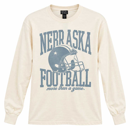 An off-white long-sleeve t-shirt with a blue graphic print reading 'NEBRASKA FOOTBALL more than a game.' and featuring a football helmet illustration, shown against a plain white background.
