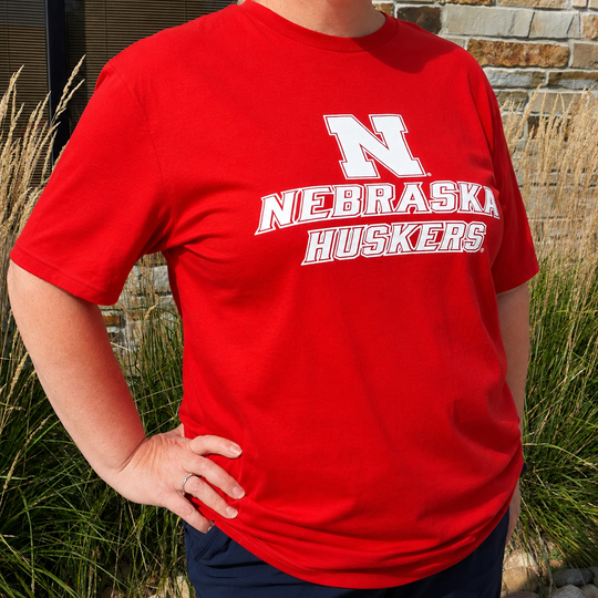 Person wearing a red 'Nebraska Huskers' t-shirt outdoors.