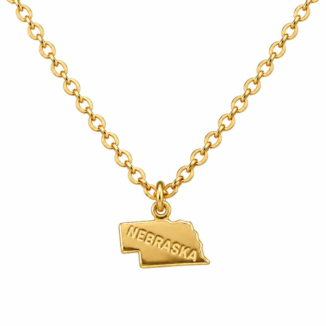 A gold chain necklace featuring a small pendant shaped like the state of Nebraska, with the word 'NEBRASKA' engraved on the front, shown against a plain white background.