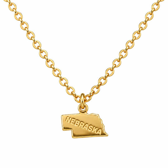 A gold chain necklace featuring a small pendant shaped like the state of Nebraska, with the word 'NEBRASKA' engraved on the front, shown against a plain white background.