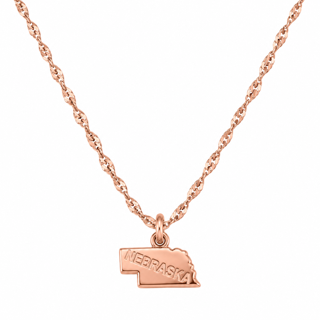 A rose gold necklace featuring a twisted chain and a small pendant shaped like the state of Nebraska, with 'NEBRASKA' engraved on the front, shown against a plain white background.