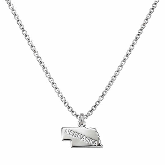 A silver chain necklace featuring a polished metal pendant shaped like the state of Nebraska, with the word 'NEBRASKA' engraved on the front, shown against a plain white background.