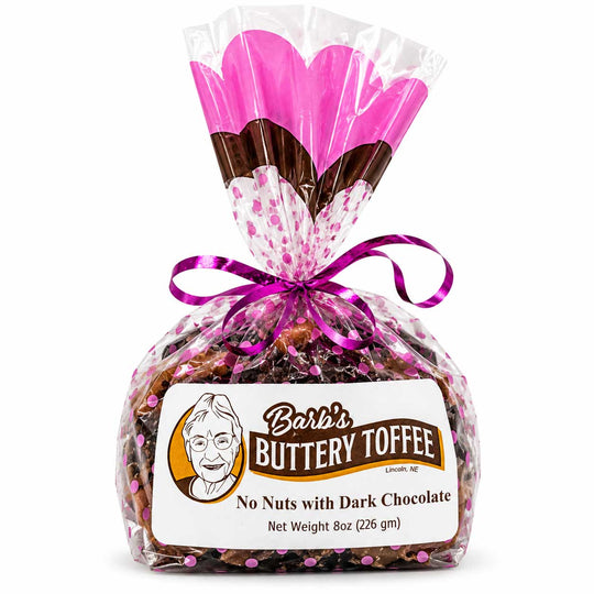 A 8 oz bag of Barb's Buttery Toffee with dark chocolate, wrapped in clear cellophane with a pink heart-patterned top, a purple ribbon, and a white product label.