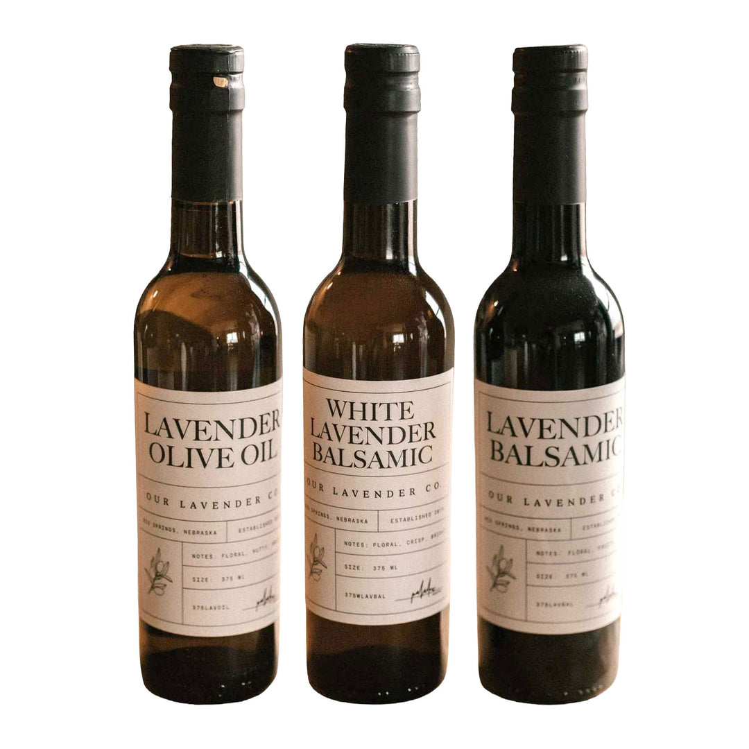 Three bottles of lavender-infused olive oil and balsamic vinegar on a white background
