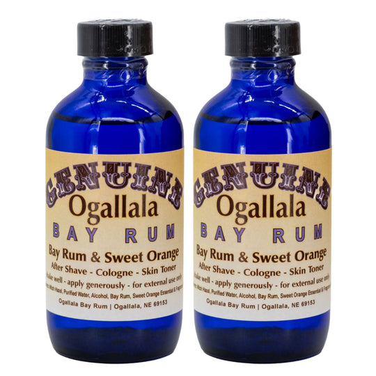 Two bottles of Ogallala Bay Rum with blue liquid and black caps on a white background.