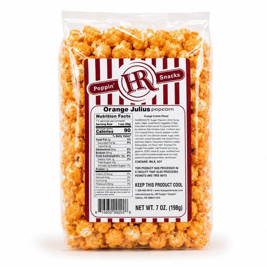 A 7 oz clear plastic bag of Poppin' HR Snacks Orange Julius popcorn on a white background, showing the orange-coated popcorn and the back of the product label with nutrition facts and ingredients.