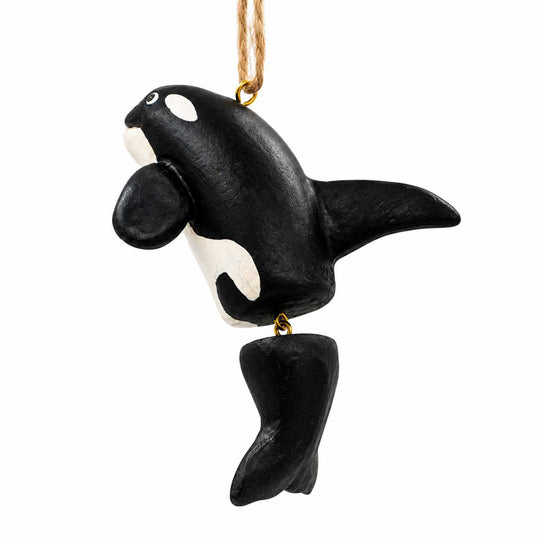A black and white painted orca whale hanging ornament with a gold-colored metal loop at the top and bottom, suspended by a natural jute string on a white background.
