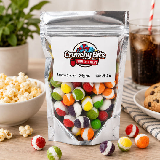 Packaging of Crunchy Bits freeze-dried treats with colorful gummy candies on a table with snacks.