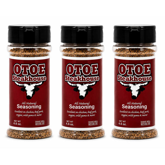 Three clear plastic bottles of Otoe Steakhouse All Natural Seasoning with black flip-top caps, arranged side by side on a white background.
