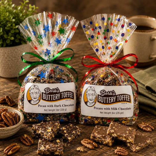Two bags of Bar's Buttery Toffee, one with green and one with red ribbons and multicolor star and polka dot wrapping, displayed on a rustic wooden table with chocolate pieces and pecans.