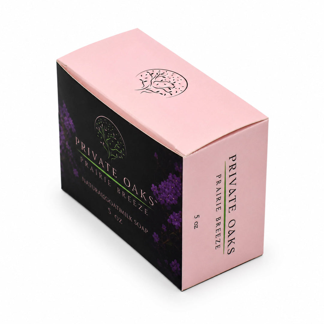 A boxed bar of Private Oaks Prairie Breeze natural unrefined soap, shown at a three-quarter angle on a white background. The packaging features a light pink top and side panel with black text, and a dark black front panel decorated with purple lavender illustrations and a green brand logo.