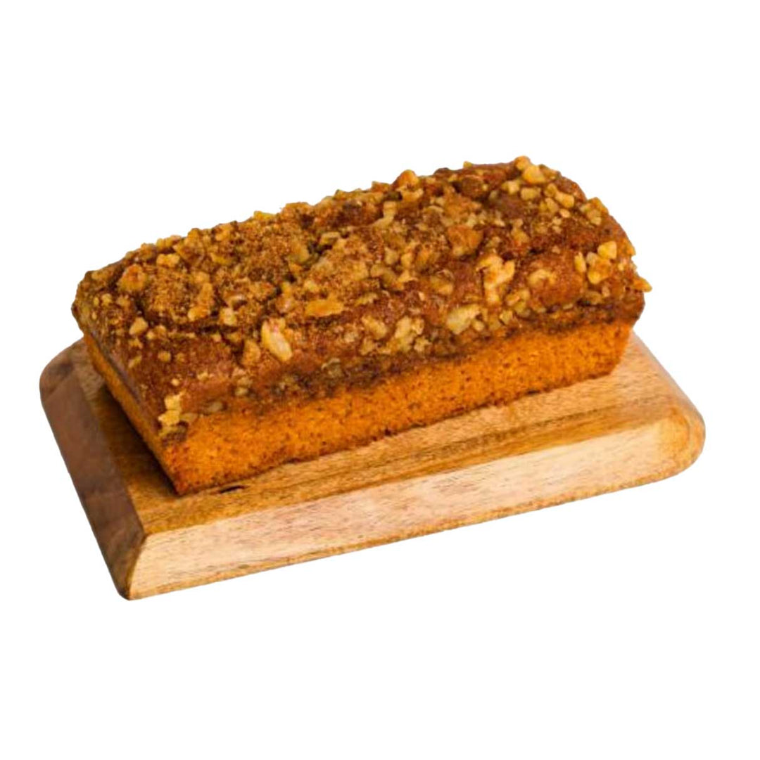 Loaf of pumpkin bread with pecans on a wooden board against a white background