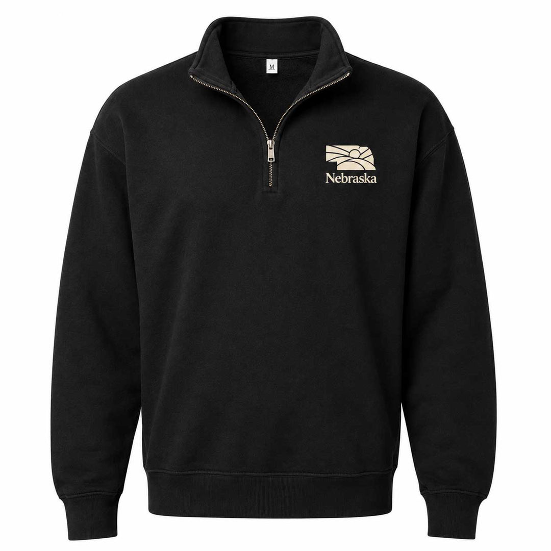A black long-sleeve quarter-zip sweatshirt with a mock neck collar, featuring a beige and white Nebraska Cornhuskers logo embroidered on the left chest, displayed on a clean white background.