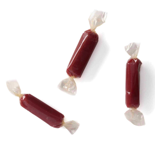 Three red caramels with white wrappers on a white background