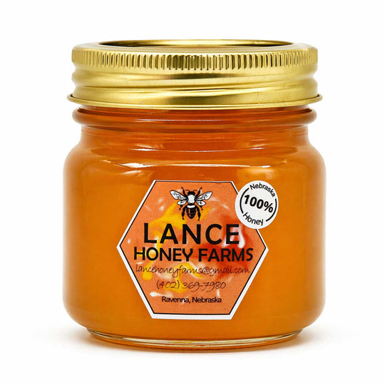 Jar of Lance Honey Farms honey with a gold lid on a white background