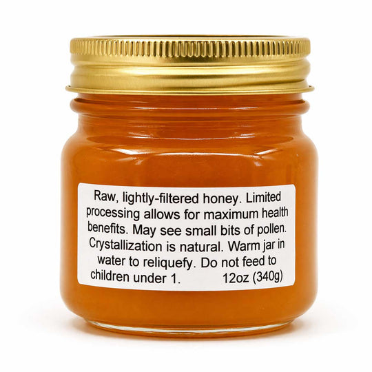 Jar of honey with a gold lid and label on a white background
