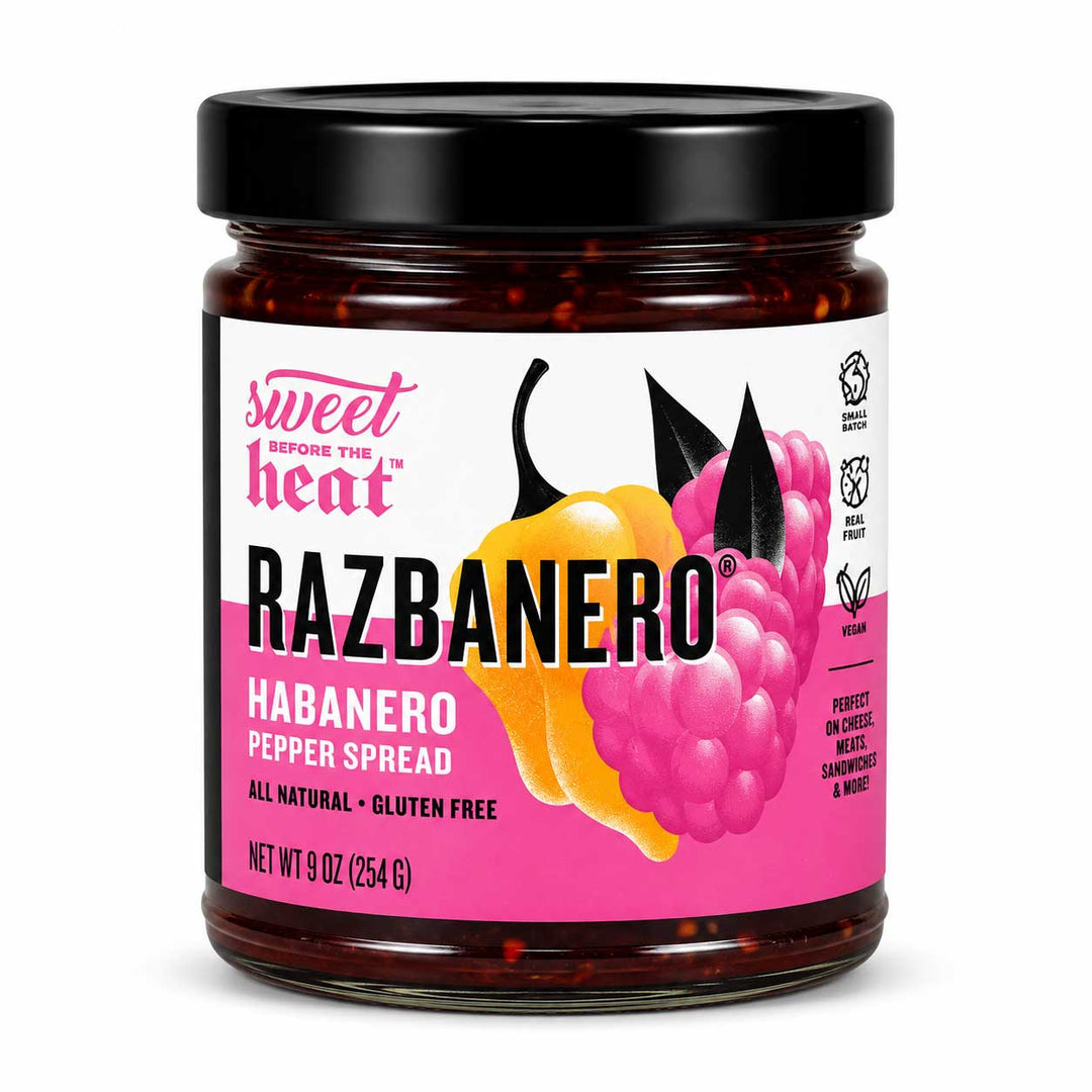 A jar of Sweet Before The Heat RAZBANERO Habanero Pepper Spread, featuring a black lid and a label with pink, yellow, and black graphics on a white background.