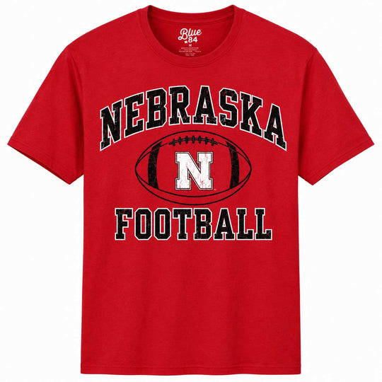 A red short-sleeve t-shirt with a 'Nebraska Football' graphic on the front, featuring a black and white football design with the letter 'N'.