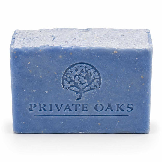 A rectangular bar of blue soap with visible speckles, embossed with a tree logo and the brand name 'PRIVATE OAKS' on the front, set against a plain white background.