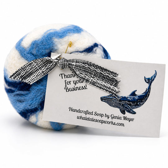 Blue and white swirled soap with a decorative bow and business card on a white background