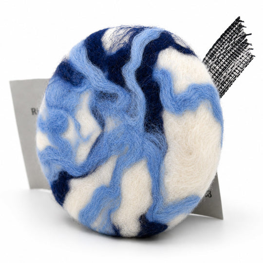 Marbled blue and white bath bomb with a black and white striped brush on a white background