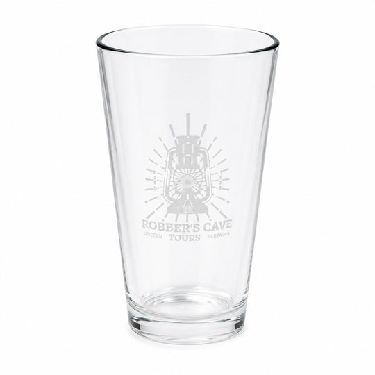 A clear glass pint glass with a frosted gray etched design featuring a lantern and the text 'Robber's Cave Tours' on the front, set against a plain white background.