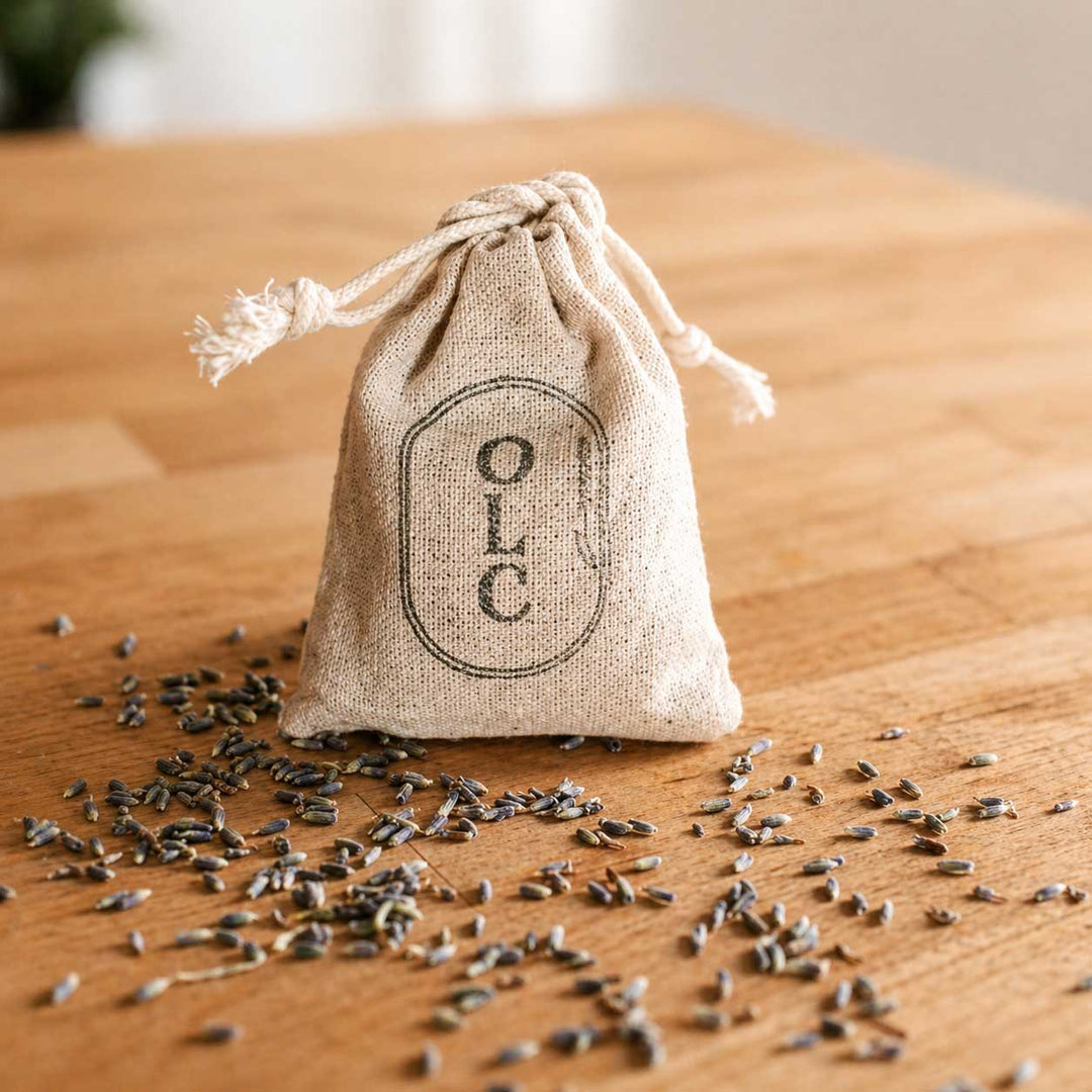Small drawstring bag labeled 'OLC' with scattered seeds on a wooden surface
