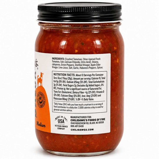 A jar of Childawg's Fine Foods Medium Heat chili oil with visible red-orange peppers and onions inside, featuring a black lid and a white label with text and a deer logo.