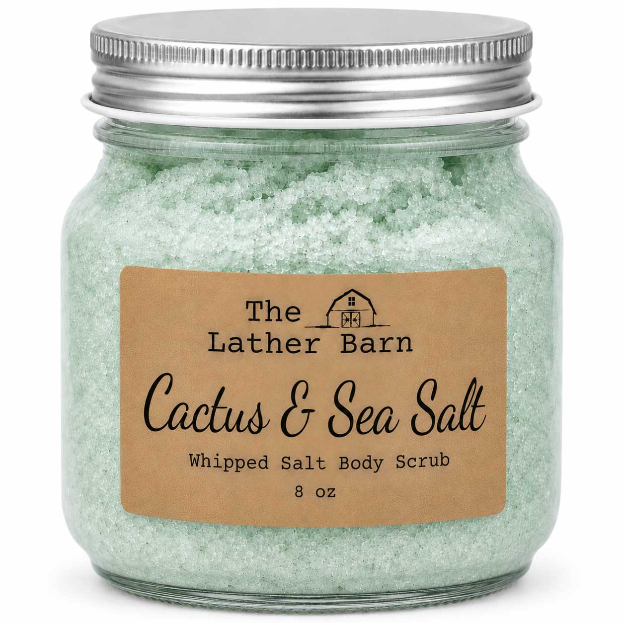 An 8 oz jar of whipped salt body scrub by The Lather Barn, featuring pale green salt crystals inside a clear glass jar with a silver metal lid and a brown kraft paper label.