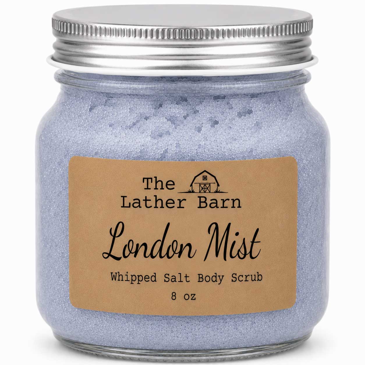 A jar of The Lather Barn London Mist Whipped Salt Body Scrub, featuring light lavender-blue scrub inside a clear glass jar with a silver metal lid and a brown kraft paper label.