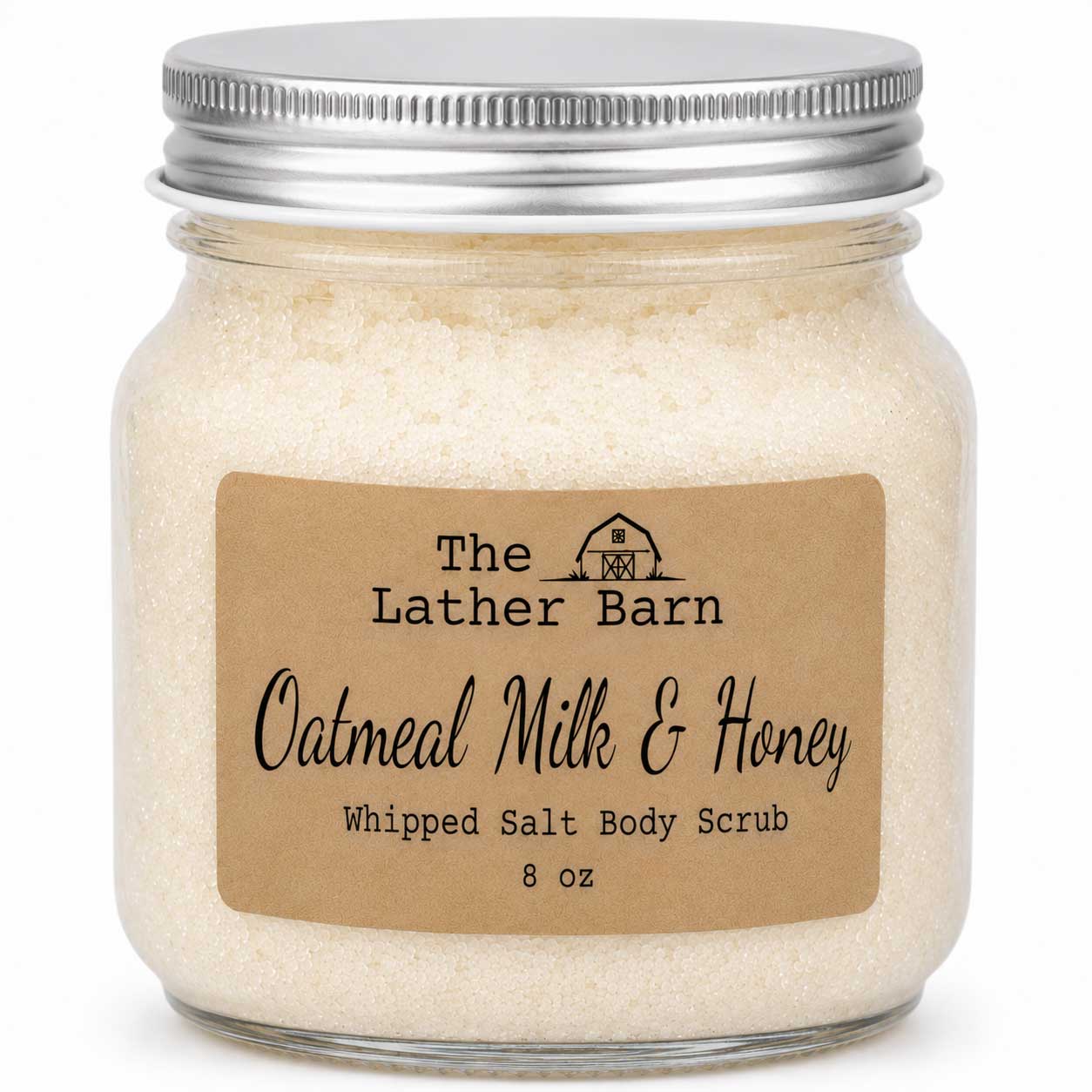 A glass jar of whipped salt body scrub with a silver metal lid and a brown kraft paper label reading 'The Lather Barn Oatmeal Milk & Honey Whipped Salt Body Scrub 8 oz'.