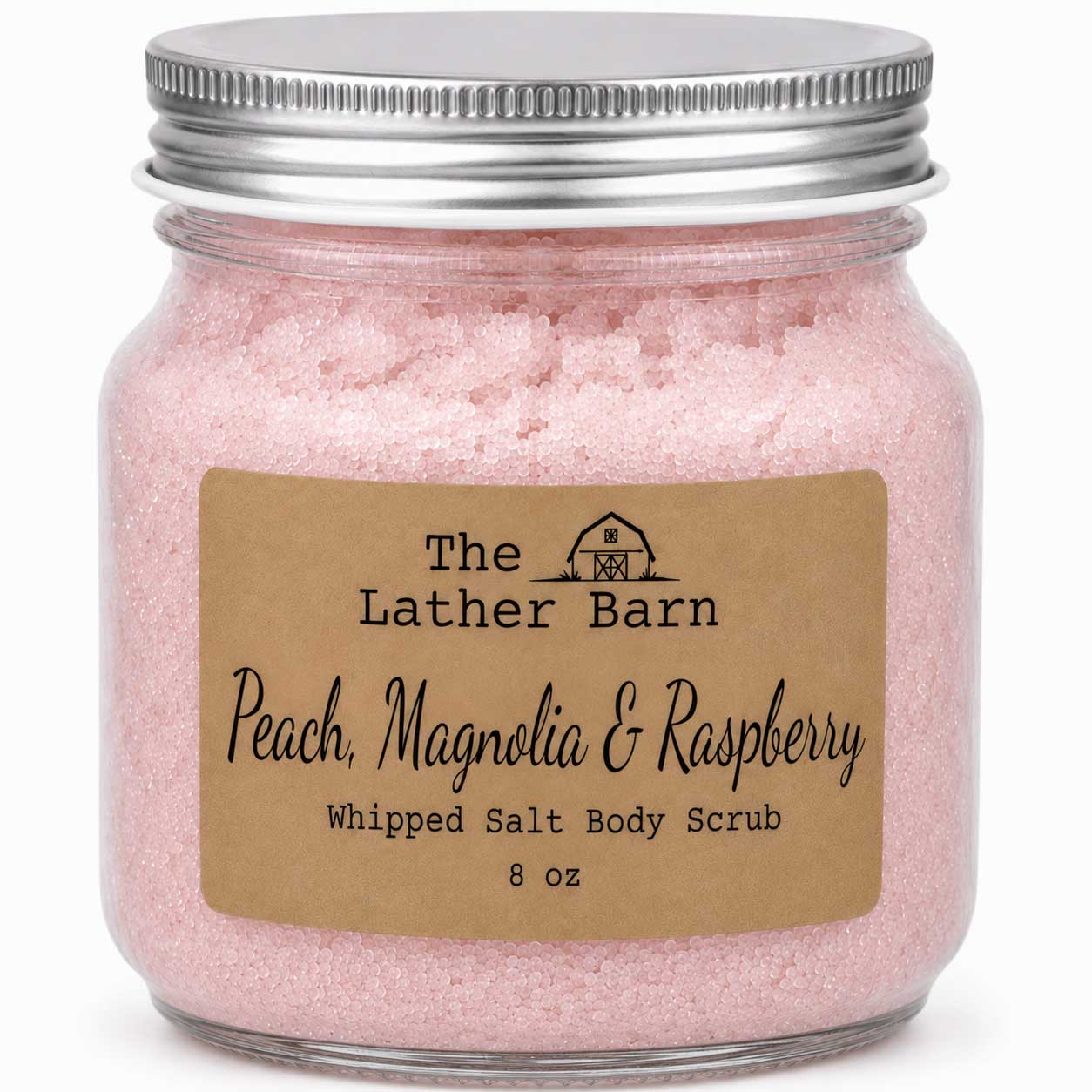 A glass jar filled with pink whipped salt body scrub, sealed with a silver metal lid and labeled 'The Lather Barn Peach, Magnolia & Raspberry Whipped Salt Body Scrub 8 oz' on a white background.