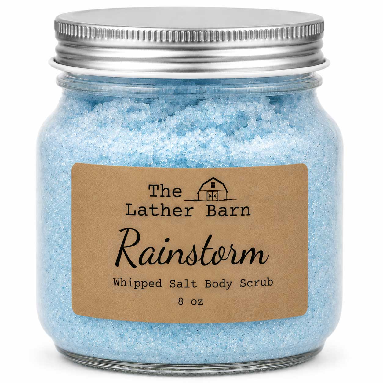 A glass jar filled with light blue whipped salt body scrub, sealed with a silver metal lid and featuring a brown kraft paper label that reads 'The Lather Barn Rainstorm Whipped Salt Body Scrub 8 oz'.