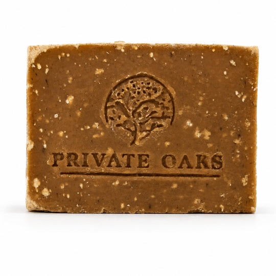 A rectangular bar of brown speckled soap with the brand name 'PRIVATE OARS' and a tree logo embossed on the front, set against a plain white background.